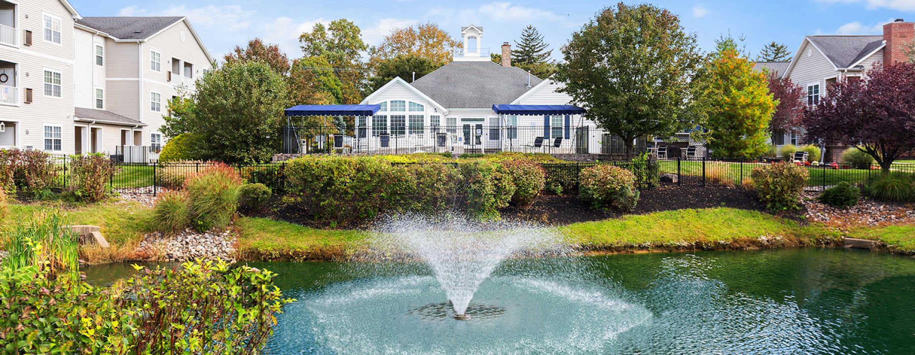 pond with fountain in front of apartment buildings